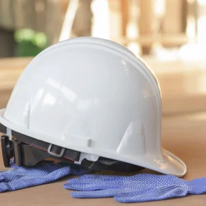 White safety helmet and blue gloves on the wooden floor.